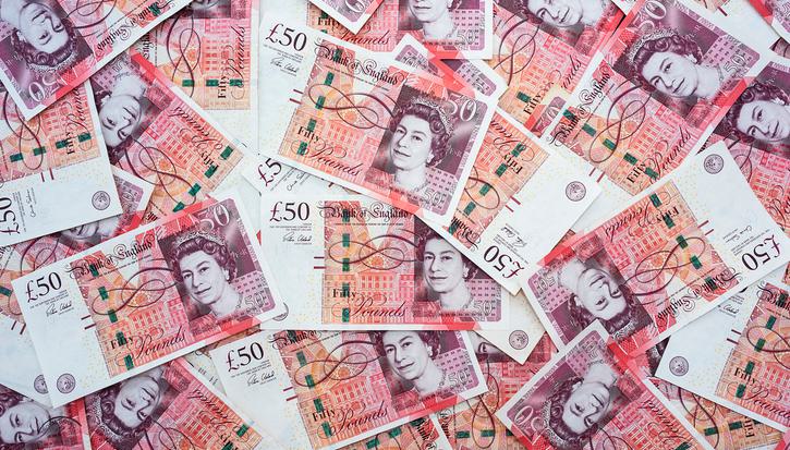 A scattered collection of overlapping fifty-pound banknotes